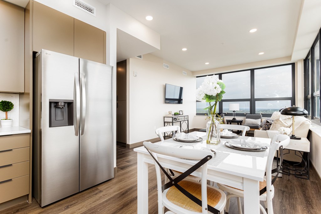 A modern kitchen with a refrigerator, table, and chairs.