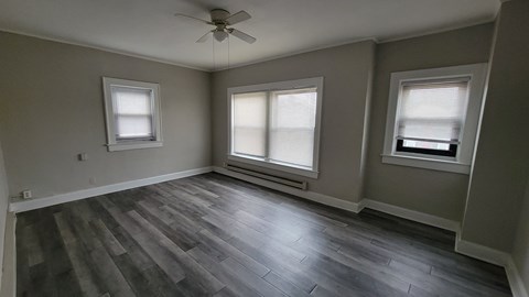 A room with a ceiling fan and three windows.