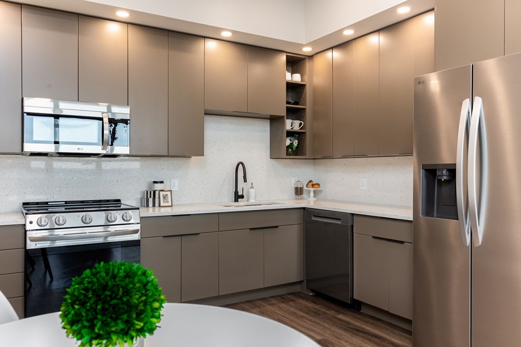 A modern kitchen with a stainless steel refrigerator and a green plant on the counter.
