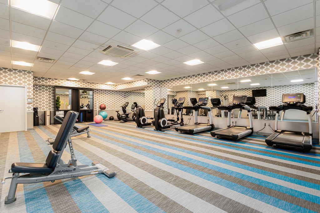 A gym with a variety of equipment including treadmills, weights, and exercise machines.