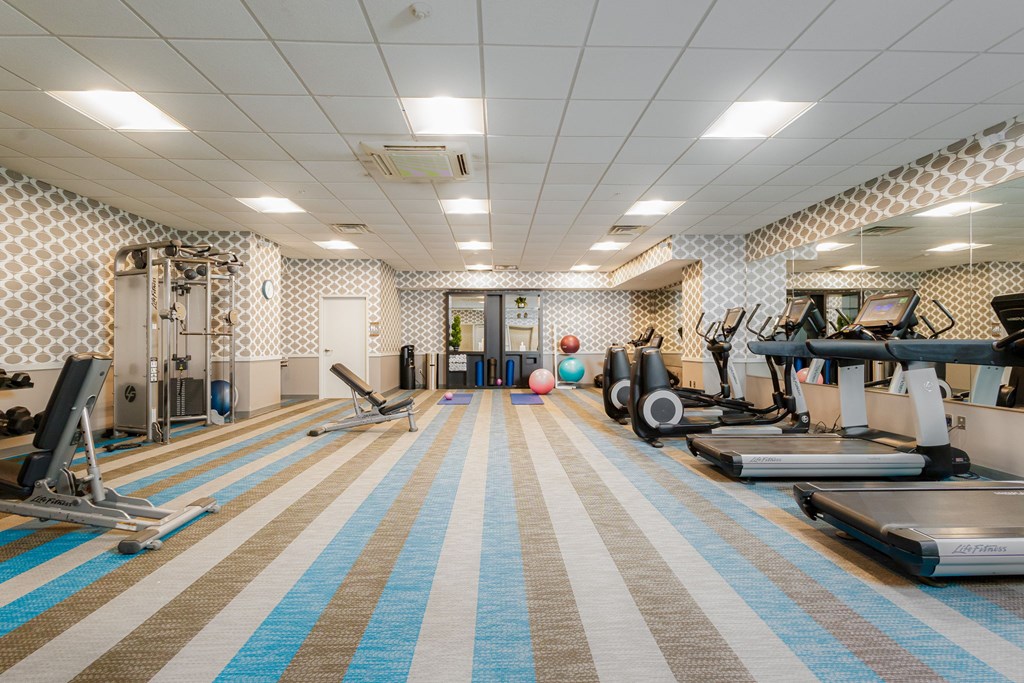 A gym with a variety of equipment including treadmills, weights, and exercise machines.