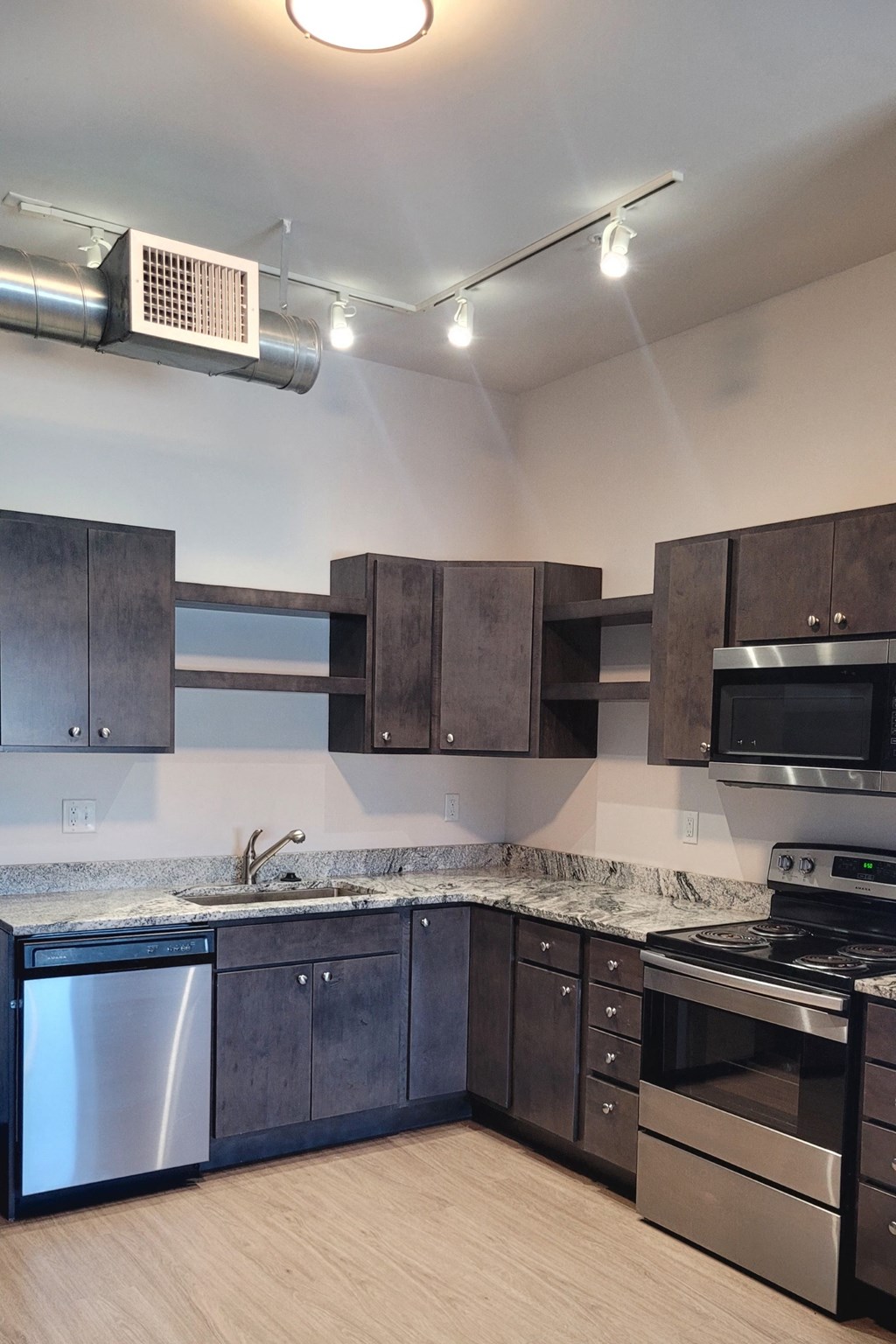 an empty kitchen with stainless steel appliances and marble counter tops