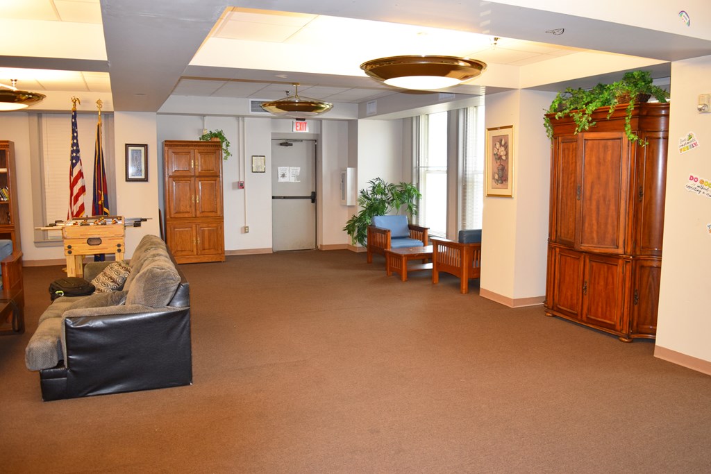 A room with a black couch and a wooden cabinet.
