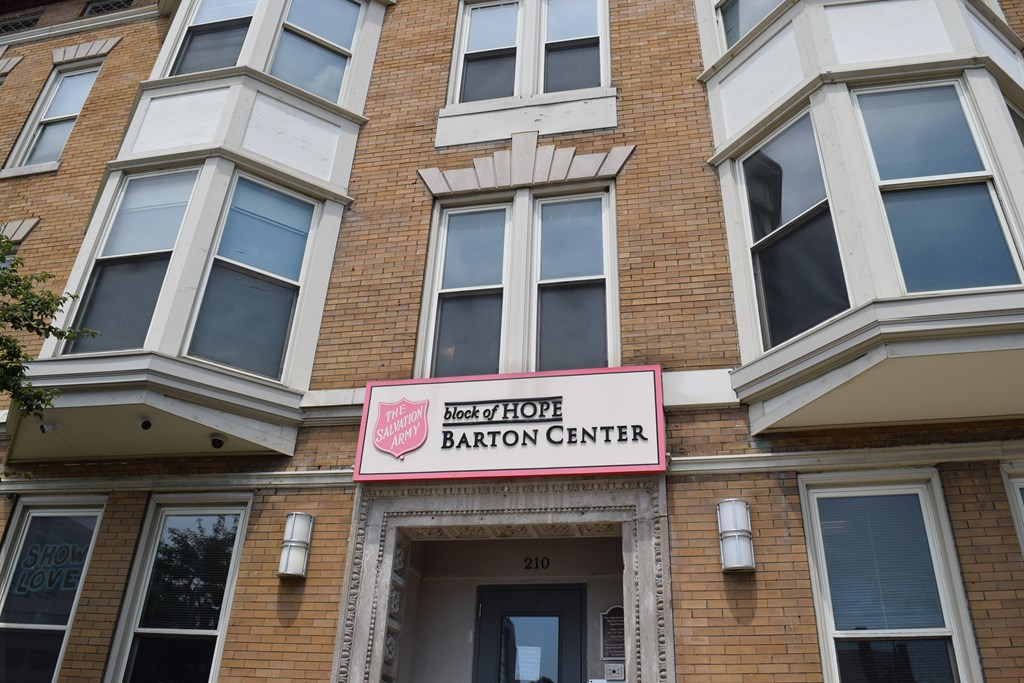 A brick building with a pink sign that says Block of Hope Barton Center.