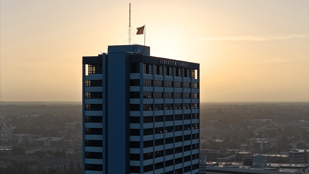 A tall building with the words "Citizen Tower" on it is shown against a sunset sky.