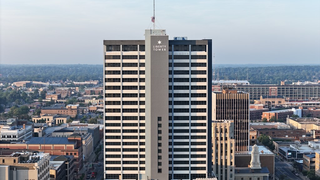 A tall building with a flag on top stands in the middle of a cityscape.