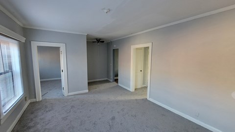 an empty living room with white walls and a ceiling fan