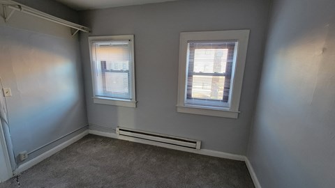 an empty room with two windows and gray walls