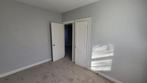 a bedroom with a door to a closet and a window with blinds