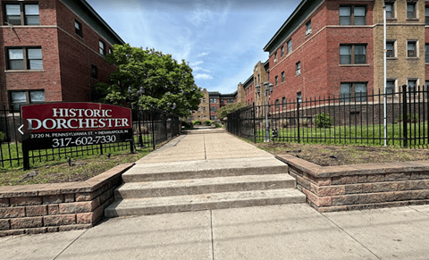 a sign for the historic apartments in front of a wrought iron fence