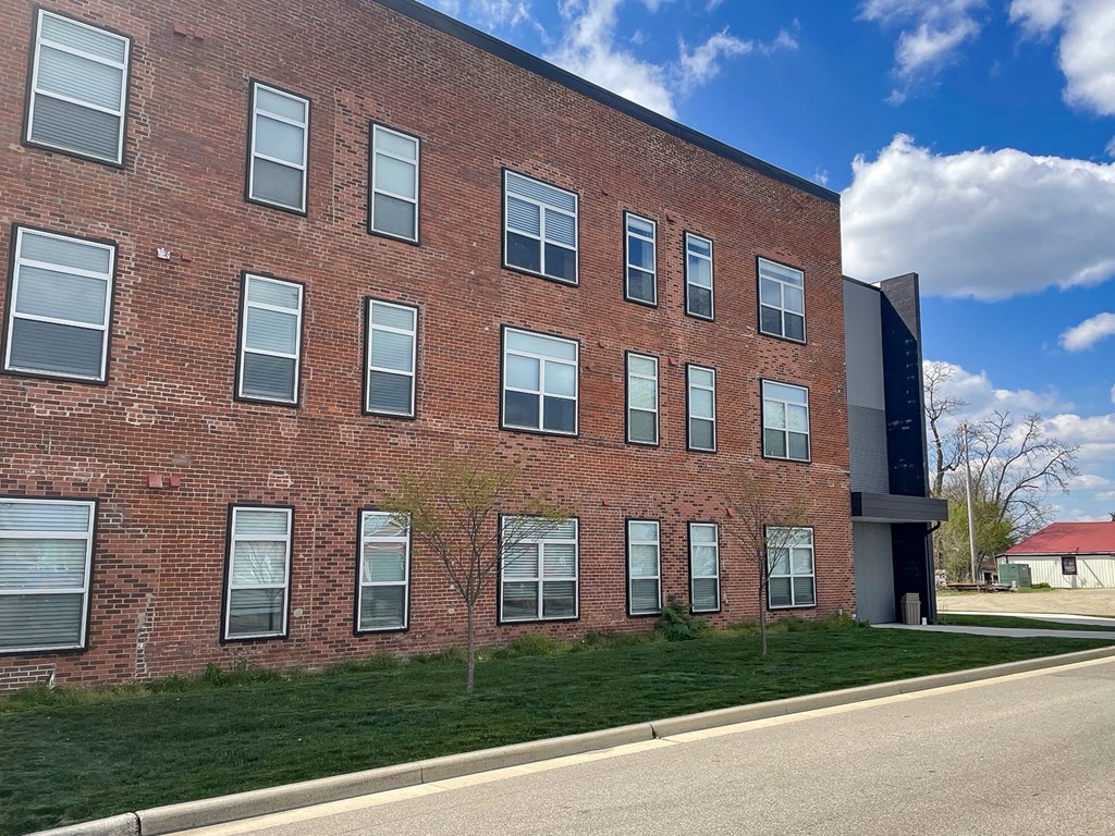 a large brick building with a grassy area in front of it