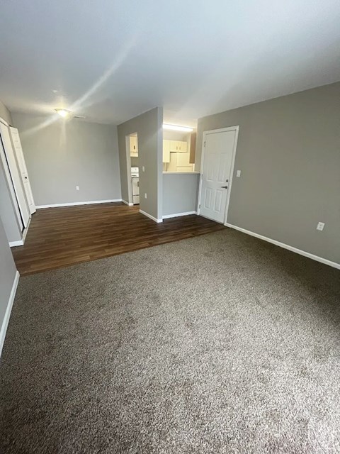 A room with a carpeted floor and a door on the right side.