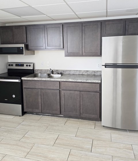 A kitchen with a black stove top oven, a sink, and a refrigerator.