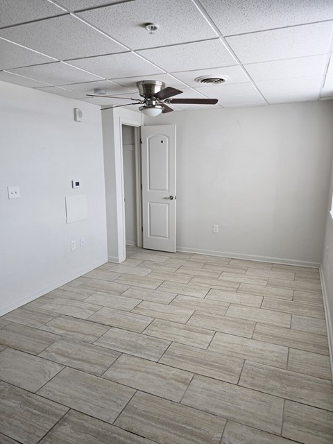A room with a ceiling fan and a door.
