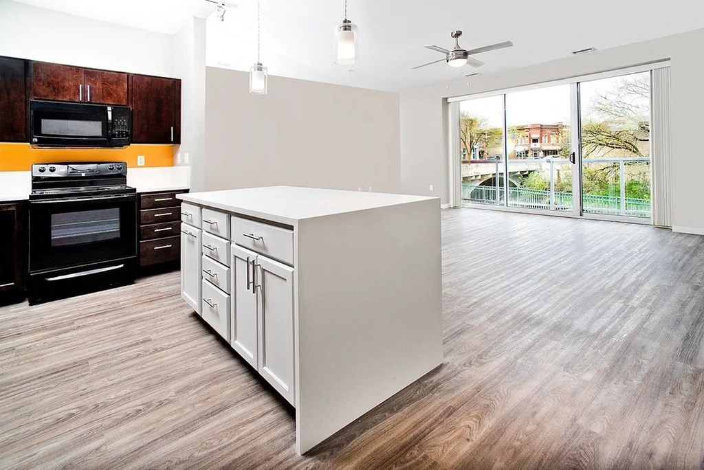 a kitchen and living room with a sliding glass door leading to a balcony