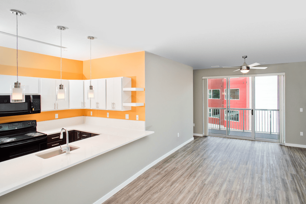 a kitchen and living room with a glass door to a balcony
