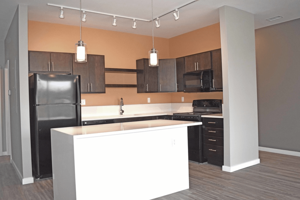 an empty kitchen with a white island and black appliances