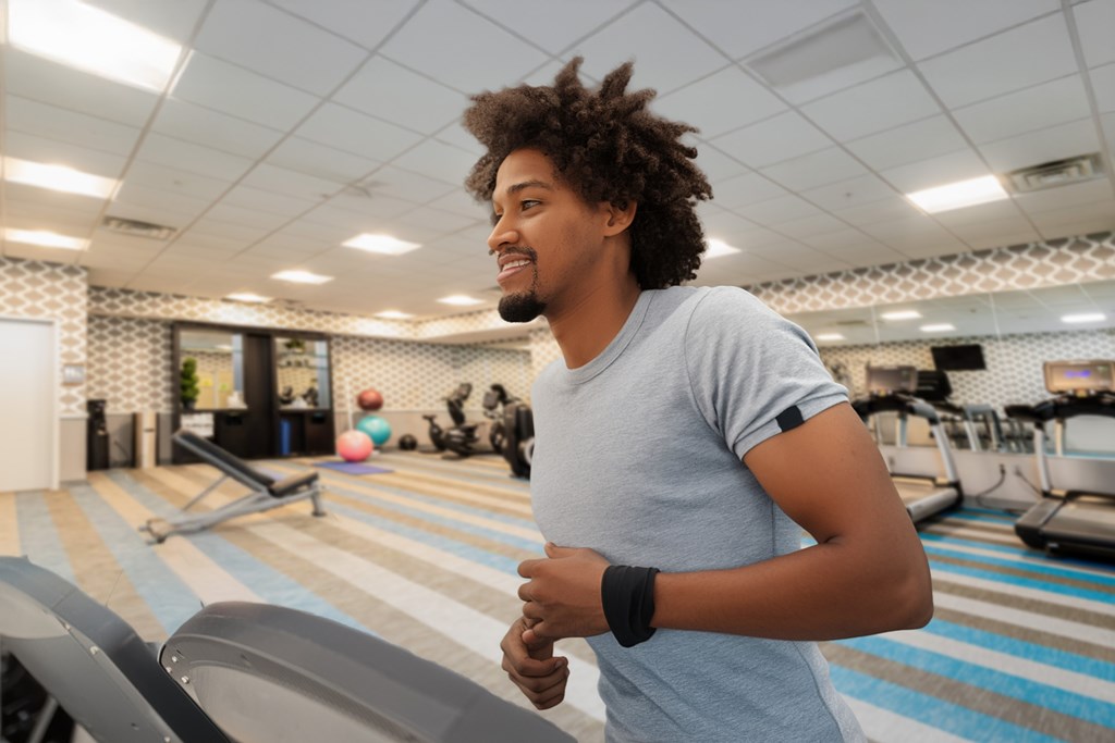 A man with a wavy hair is running on a treadmill in a gym.
