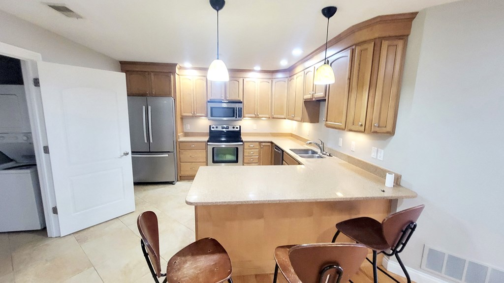 A kitchen with a white counter top and brown chairs.