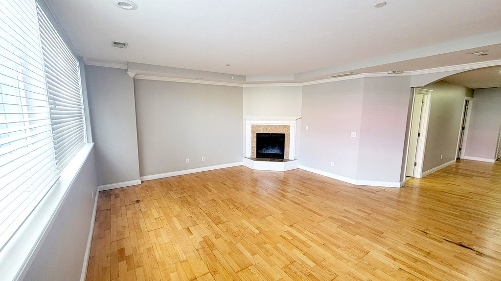 A room with wooden flooring and a fireplace.