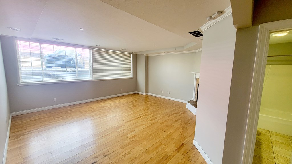 A room with wooden flooring and a window with blinds.
