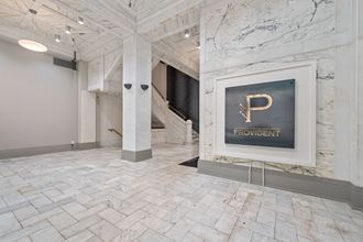 a view of the lobby with a sign on the wall and a marble staircase in the background