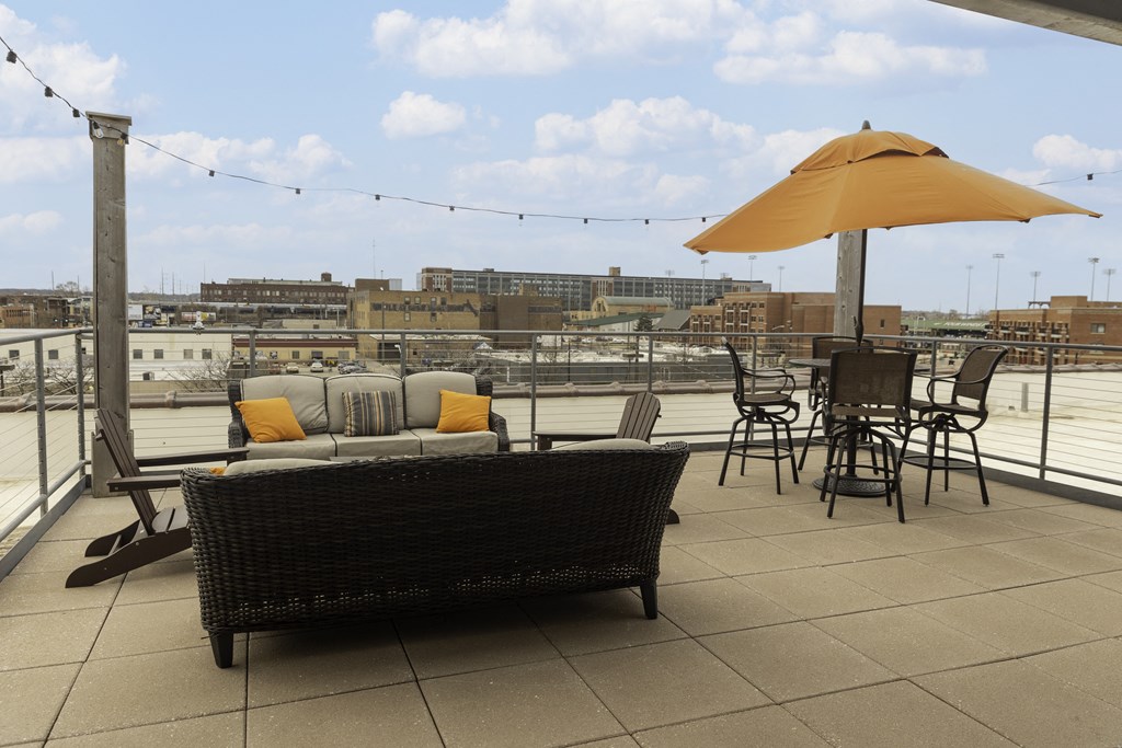 a rooftop patio with a couch and chairs and an umbrella