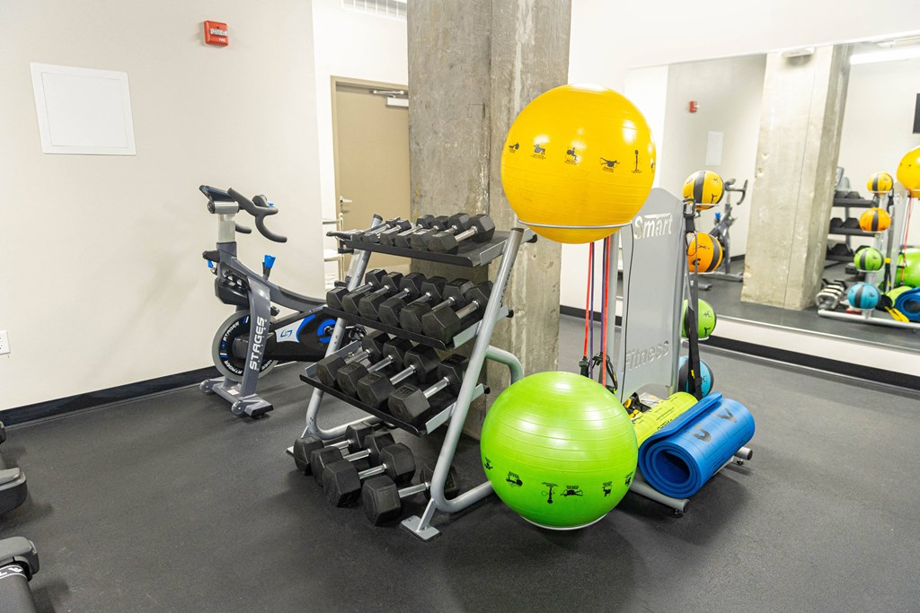 a fitness room with weights and a yellow ball in the middle of it