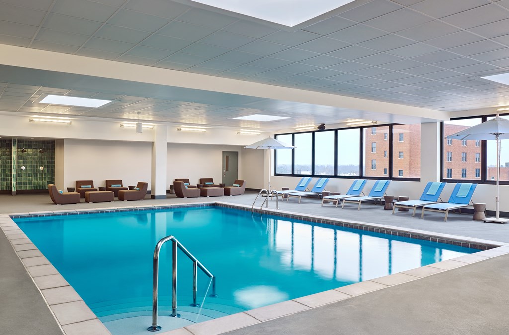 A large indoor swimming pool with lounge chairs and a glass wall.
