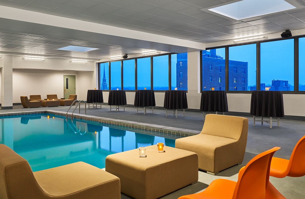 A room with a pool, chairs and a table.