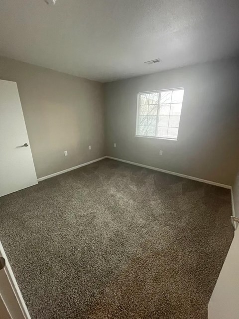 A room with a carpeted floor and a window.