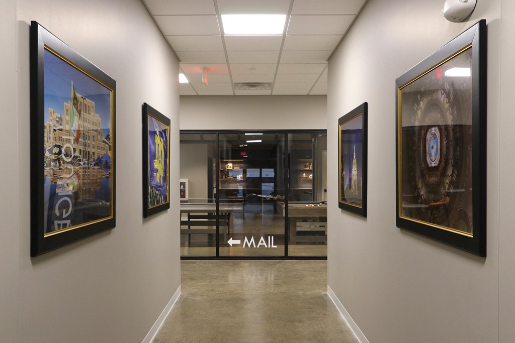 a hallway with paintings on the wall and a glass door