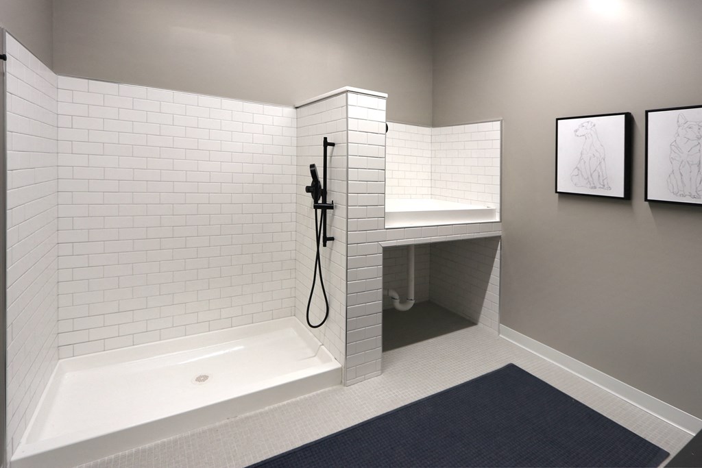 a white tiled bathroom with a shower and a sink