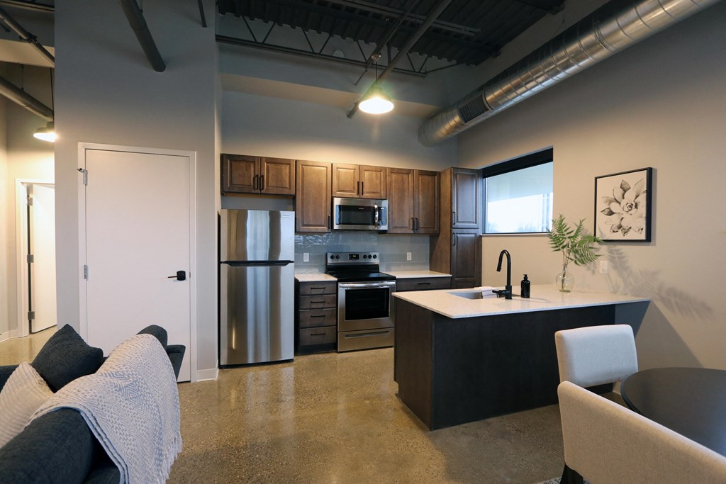 a kitchen with stainless steel appliances and wood cabinets in an open floor plan