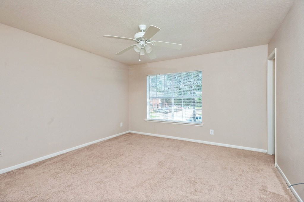 Bedroom with ceiling fan and window at Park Village Apartments in Conroe TX