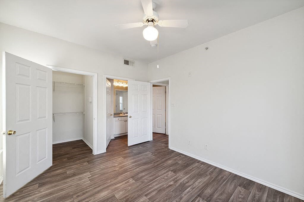 Two Bedroom Apartments in North Dallas TX - Tivoli - Well Lit Bedroom with Wood Plank Flooring, Oversized Closet, Large Windows, and En Suite Bathroom
