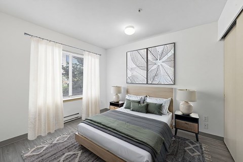 A bedroom with a large bed, a window with curtains, and a rug on the floor.