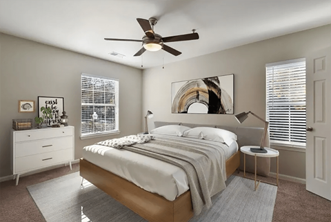 A bedroom with a bed, a ceiling fan, and a nightstand with a lamp.