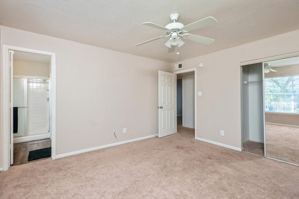 Carpeted bedroom with ceiling fan at Park Village Apartments in Conroe TX