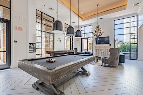 A pool table is in the middle of a room with a television and a chair.