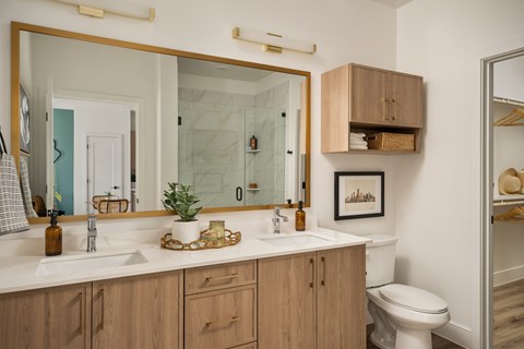 A bathroom with a white counter top and wooden cabinets.