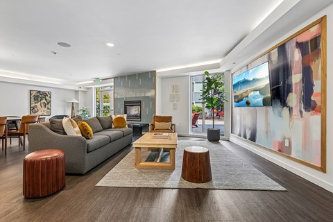 A modern living room with a grey sofa, wooden coffee table, and a large abstract painting on the wall.