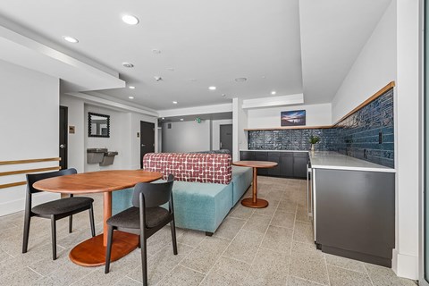 A kitchen with a table and chairs in the foreground and a refrigerator in the background.