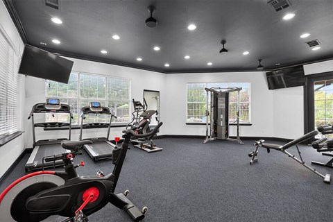 A spacious gym with a variety of exercise equipment including treadmills, stationary bikes, and weight machines.