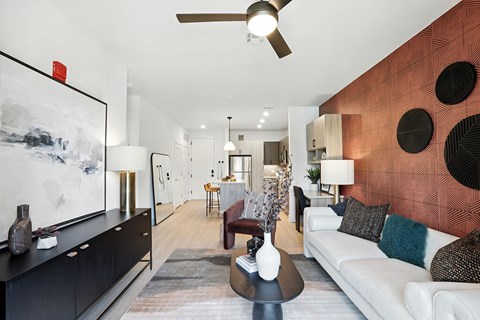 A living room with a white couch and a red accent wall.