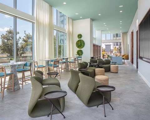 A modern lounge area with green chairs and tables.