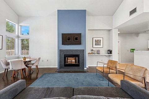 A living room with a fireplace and a grey couch.