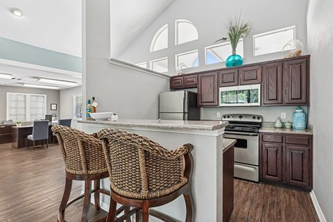 A kitchen with a white counter top and brown chairs.