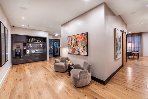 A living room with a grey sofa and a painting on the wall.
