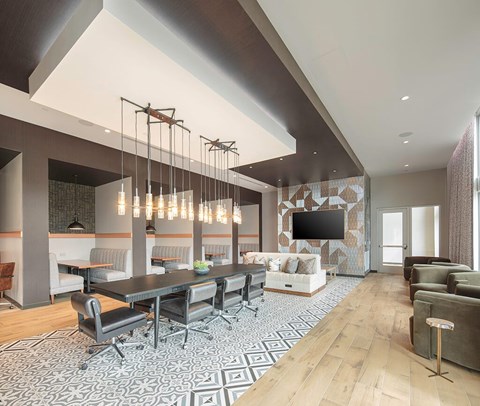 A modern living room with a long black table and grey chairs.